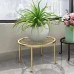 Modern circular Metal Plant Stand Pakistan with wood shelf holding an orange flower pot stand.