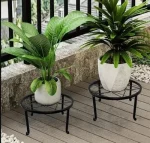 Modern circular Metal Plant Stand Pakistan with wood shelf holding an orange flower pot stand.
